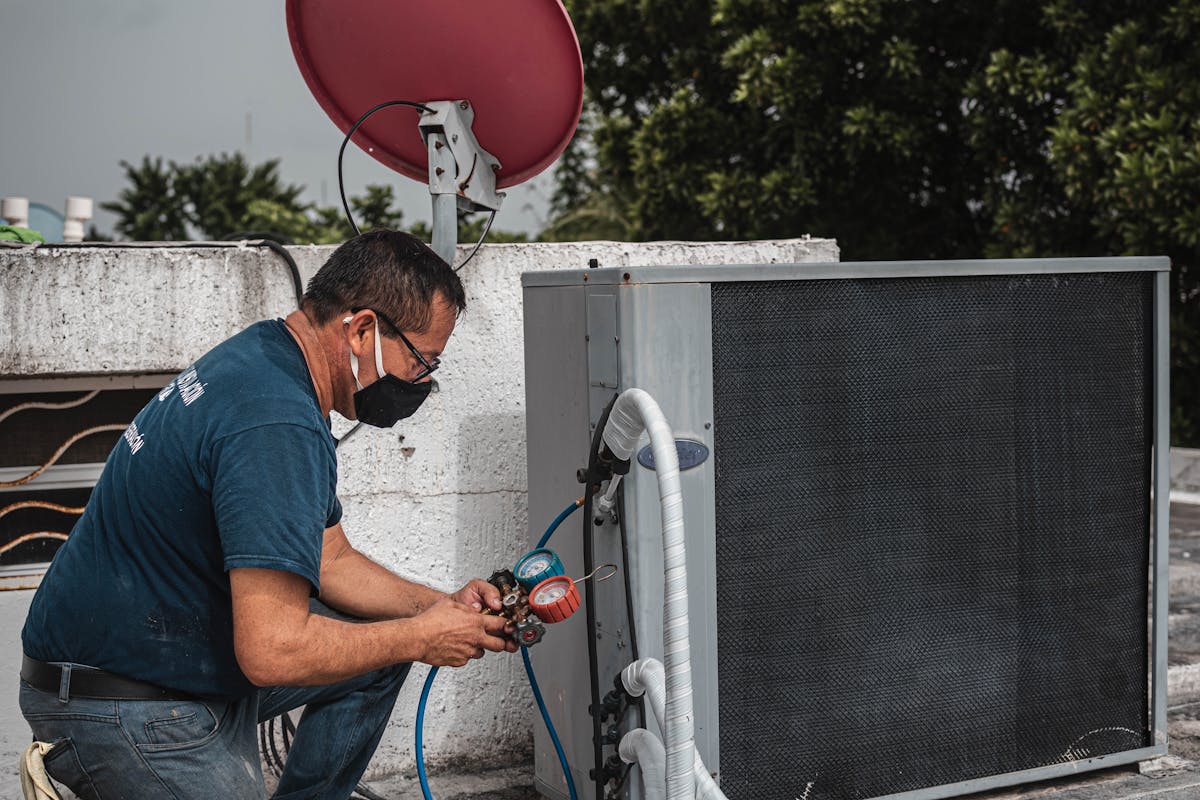 Technician checking air conditioning refrigerant pressures with gauges