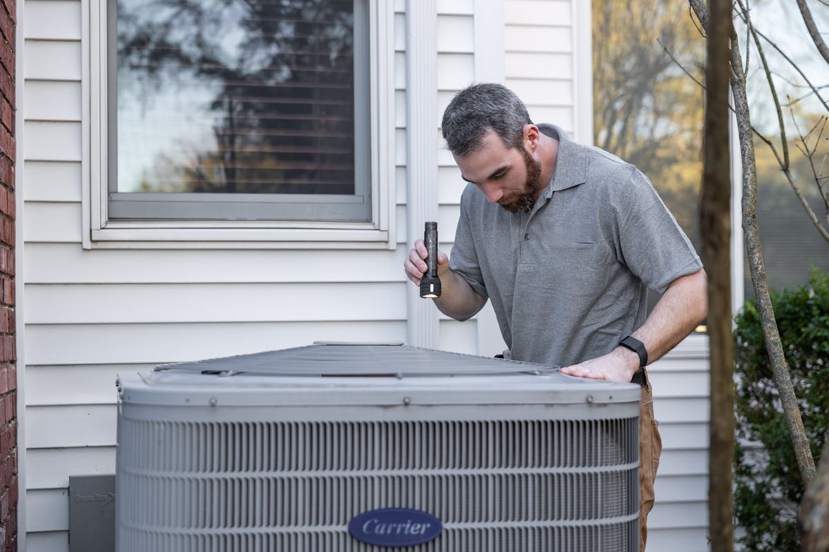 HVAC technician inspecting outdoor air conditioning unit